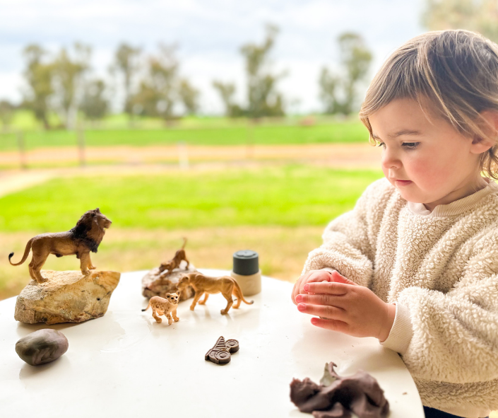 The girl is playing with playdough and animals